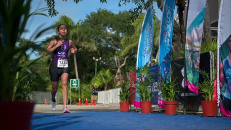 Cámara-Lenta-De-Una-Joven-Atleta-Con-Traje-Morado-Corriendo-Hasta-La-Línea-De-Meta-En-Una-Competencia-De-Triatlón