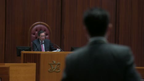 A-lawmaker-speaks-as-Hong-Kong-Legislative-Council-President,-Andrew-Leung-listens-to-the-speech-during-a-meeting-at-the-Legislative-Council's-main-chamber-in-Hong-Kong