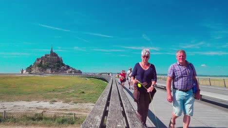 Turistas-Caminando-Por-La-Pasarela-Mont-saint-michel-Durante-Un-Día-Ventoso