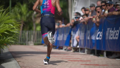 Atleta-Masculino-Latino-Corriendo-Pasando-Por-Una-Multitud-De-Espectadores-Animando-A-Los-Participantes-En-Una-Competencia-De-Triatlón