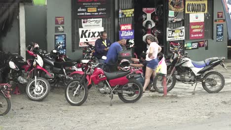 Motocross-bike-repair-shop-with-assorted-models-and-a-female-client-looking-at-repairs,-Advancing-Slow-Motion-shot