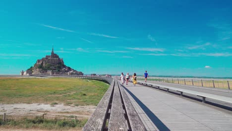 Tourists-are-walking-on-Pont-passerelle,-the-famous-bridge-by-Mont-Saint-Michel