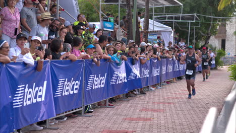 Gruppe-Männlicher-Athleten,-Die-Bei-Einem-Triathlon-Wettkampf-Neben-Den-Zuschauern-Joggen