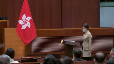 Die-Frühere-Vorstandsvorsitzende-Von-Hongkong,-Carrie-Lam,-Leitet-Die-Eidzeremonie,-Um-Das-Bündnis-Mit-Dem-Grundgesetz-Zu-Schwören,-Während-Sie-Neben-Der-Flagge-Hongkongs-In-Der-Hauptkammer-Des-Legislativrates-Steht