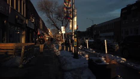 Exterior-sunset-shot-of-pedestrians-walking-on-Danforth-Avenue-in-Toronto-during-the-winter