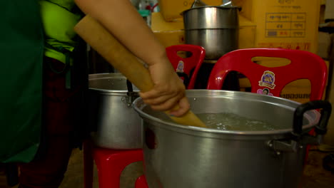 Thailand,-Bangkok---13-August-2022:-Unrecognizable-worker-stirring-filtered-coconut-water