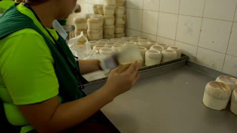 Thailand,-Bangkok---13-August-2022:-Woman-worker-extracting-coconut-pulp-from-the-shell-using-scraper