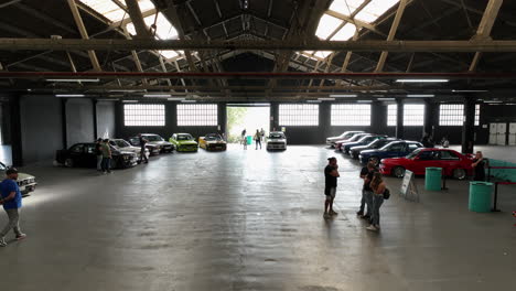 Indoor-Show-Mit-BMW-E30,-Oldtimer-In-Knalligen-Farben,-Luftaufnahme,-Viele-Fans