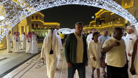 Personas-Con-Vestimenta-árabe-Para-Hombres-Y-Mujeres-Caminan-En-Una-Calle-De-Lujo-En-Katara-Qatar-Doha-Arquitectura-Antigua-Pequeña-Cadena-De-Luz-Led-Estructura-De-Decoración-De-Fútbol-Y-Centro-Comercial-De-Joyería