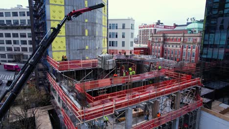 Aerial-view-over-cranes-lifting-material-to-a-construction-site-on-Jackson-Avenue,Queens,-NY---rising,-drone-shot