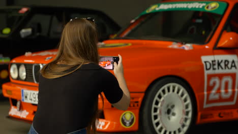 Una-Mujer-Toma-Fotos-De-Los-Autos-Bmw-E30-En-Una-Exhibición-De-Reuniones-De-Fans-En-Interiores,-Cierra