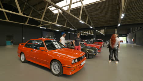 Toma-De-Cardán-Baja-Dando-Vueltas-Alrededor-Del-Bmw-E30-Naranja-Con-Gente-Mirando-Alrededor