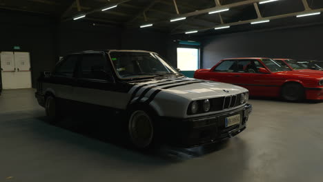 Toma-Cinematográfica-De-Establecimiento-Del-Bmw-E30-Estacionado-En-Una-Reunión-De-Exhibición-En-Interiores