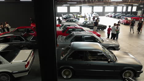 Aerial-panning-view-across-old-school-BMW-e30-classic-car-show-warehouse-exhibition