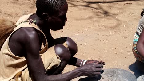 Miembro-De-La-Tribu-Hadzabe,-Hombre,-Comiendo-Una-Rata-Al-Lado-De-La-Hoguera