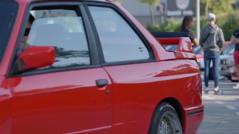 Classic-red-BMW-e30-passengers-arriving-at-Barcelona-car-show-fan-meeting