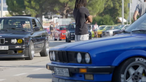 Exterior-shot-of-classic-BMW-e30-meeting,-closeup-of-blue-and-black-car-behind