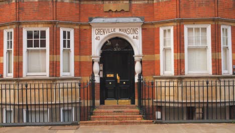 Father-And-Kid-Walking-By-The-Facade-And-Entrance-Of-Grenville-Mansions-In-London,-UK