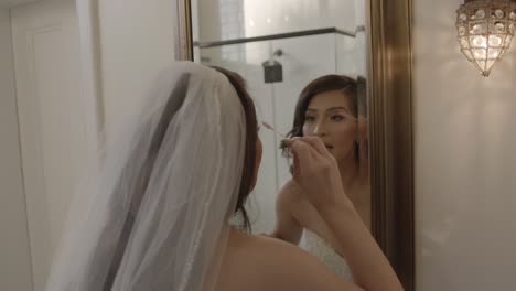 Bride-looking-in-the-mirror,-touching-up-her-makeup