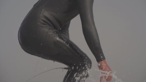 Close-up-of-Surfer-takes-off-and-rides-the-wave-on-a-longboard,-Shot-from-Behind