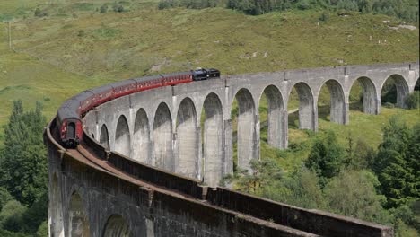 Landscape-with-famous-Glenfinnan-Viaduct-in-Scotland-and-Hogwarts-Express-train-full-of-tourists