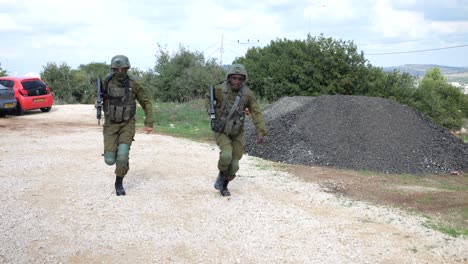 Zwei-Soldaten-Der-Israelischen-Verteidigungskräfte-In-Militäruniform-Mit-Gewehren,-Die-In-Zeitlupe-Auf-Dem-übungsplatz-Auf-Die-Kamera-Zulaufen