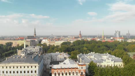 Bird's-aerial-view-of-Riga-cityscape-from-Esplenade-park,-sunny-summer-day,-Latvia,-pan-left