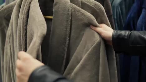 Closeup-view-of-man's-hands-choosing-a-bathrobe-in-the-store-of-bed-linen-and-accessories