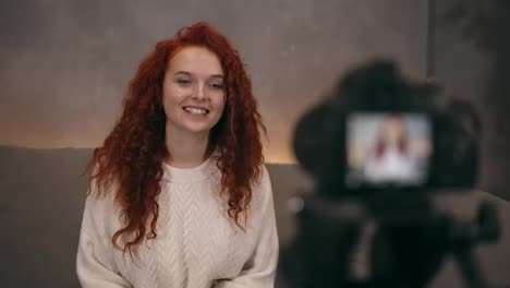 Portrait-of-redhead-young-girl-vlogger-is-talking-in-front-of-camera-recording-video-for-online-blog-for-her-followers