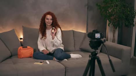 Curly-redhead-young-girl-beauty-vlogger-is-talking-in-front-of-camera-recording-video-for-online-blog-in-internet