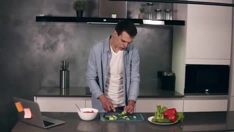 Joven-Caucásico-Con-Ropa-Informal-Cocinando-Un-Desayuno-Vegetariano-Cortando-Verduras-Para-Ensalada-En-La-Cocina-De-Su-Casa-Y-Bailando