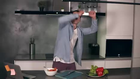 Active-caucasian-young-man-enjoying-funny-dance-standing-in-modern-grey-coloured-kitchen,-happy-funky-independent-guy-dancing