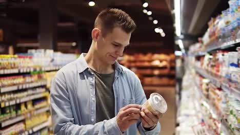 and-attractive-tall-guy-in-supermarket.-Caucasian-smiling-young-man-in-blue-shirt-choosing-fresh-milk-from-the-fridge-on-store