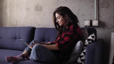 Beautiful-girl-in-her-20's-typing-something-on-laptop-keyboard-while-she-is-chilling-out-on-the-sofa