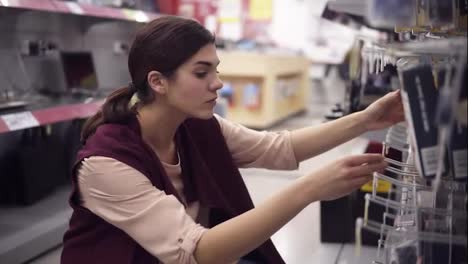 Young-beautiful-female-costumer-choosing-HDMI-cable-in-electronics-store.