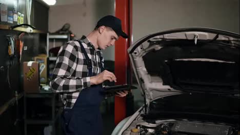 Mechanic-inspects-the-car-undercarriage-way-with-a-digital-tablet