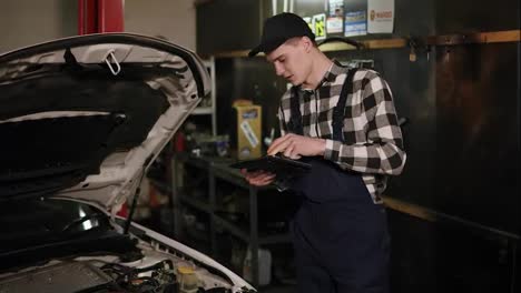 Mechanic-inspects-the-car-undercarriage-way-with-a-digital-tablet