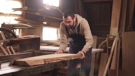 Caucasian-man-is-working-in-his-workshop.-Concentrated-sawing-a-wood-on-and-electric-machine