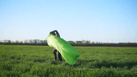 Un-Hombre-Intenta-Atrapar-El-Viento-Para-Hacer-Una-Cama-Inflable.-Color-Verde.-Hermosa-Pradera.