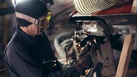 Workman-with-protective-eyewear-is-grinding-metal-construction-with-circular-saw