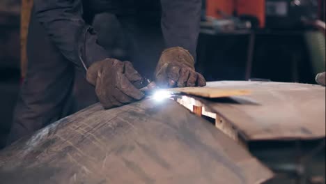 Workman's-hands-cutting-metal-with-torch-using-wood-plank-to-adjust-and-even-line