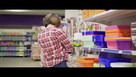 A-young-woman-in-check-shirt-is-choosing-plastic-box-in-the-shopping-center.-4k