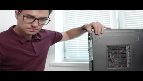 Close-Up-view-of-a-concentrated-computer-service-worker-in-glasses-finishing-upgrading-computer-hardware.-Support-team.-Computer