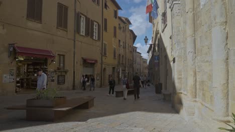 Turistas-Caminando-Por-Las-Tranquilas-Callejuelas-De-La-Ciudad-Amurallada-De-Volterra,-Provincia-De-Perugia,-Italia