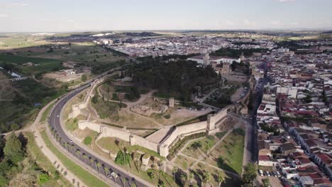 Old-medieval-castle-walls-outside-of-city-skyline-Badajoz-in-Spain,-aerial-dolly