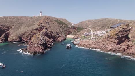 Scenic-drone-view-of-Berlengas-grande-port,-ships-moored-near-cliffs