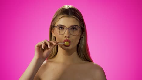 Cute-European-woman-licks-a-yellow-lollipop-in-slow-motion,-isolated-background