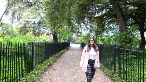 Woman-walking-on-path-with-leaves-and-runner-in-background-in-Phoenix-Park
