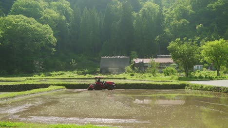 Granjero-Arando-Un-Campo-De-Arroz-Parcialmente-Inundado-Con-Un-Tractor-En-El-Campo-De-Shirakawago