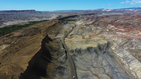 Aerial-view-overlooking-a-vehicle-driving-on-a-desert-road-in-middle-of-south-USA